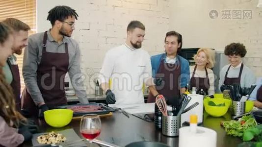 不同的人群穿着围裙在厨房烹饪课程中烹饪食物视频