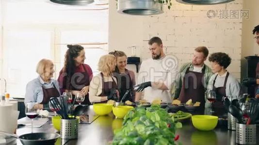 一群男人和女孩拍手给厨师，在厨房里拿着熟食视频