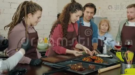 快乐的年轻女子在厨房里和一群烹饪班的学生一起做饭视频