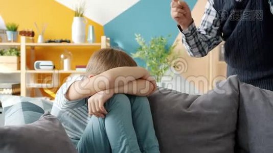 严厉的祖父惩罚小男孩对坐在沙发上哭泣的孩子摇着手指视频
