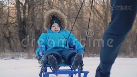 父母在冬天带着快乐的小男孩在雪橇上。 幼儿玩雪橇。 家庭圣诞节的户外乐趣视频