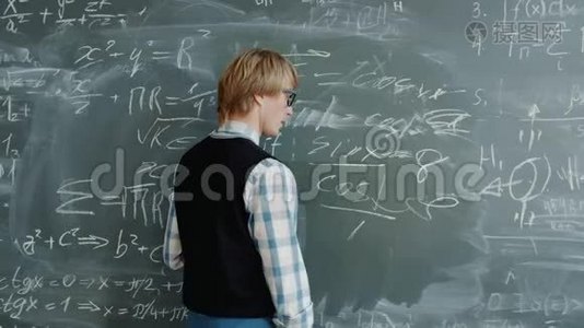 数学教师在黑板上写公式的肖像，然后看着摄像机说话视频