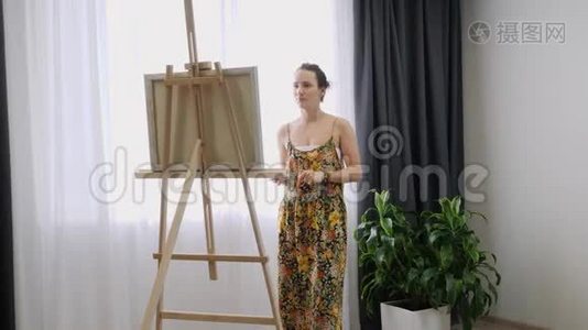 艺术家在画布上作画，涂抹画笔。 帆布站在画架上。 女人在画架上画画。 女画工作室视频