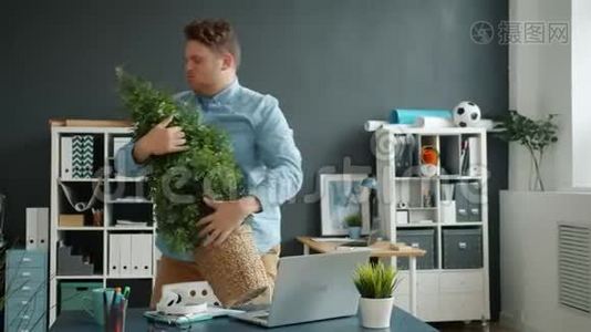 有趣的家伙在现代办公室和绿色盆栽跳舞在室内玩视频