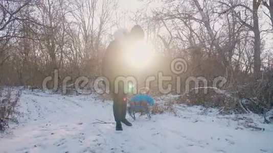 妈妈带着一个孩子坐在雪覆盖的森林上的雪橇上。 开朗的寒假观念..视频