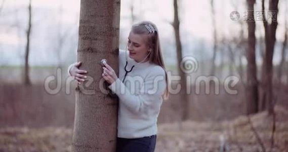 女人用听诊器检查森林里的一棵树视频