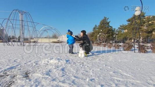 小男孩和他妈妈在雪地公园玩得很开心。 快乐的家庭在冬天玩雪。 活跃的冬季游戏。视频