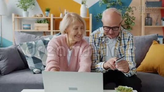 在家使用笔记本电脑用银行卡在线支付的快乐老人视频