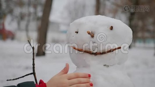 快乐女孩在冬季公园堆雪人。 寒假和圣诞节的概念。视频