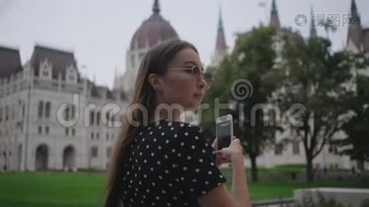 一名女子正在匈牙利国会大厦用手机拍照视频