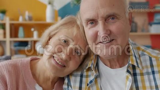 一对恩爱夫妻在家看镜头时微笑的老人和男人的画像视频