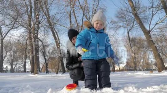 小男孩和他妈妈在雪地公园玩得很开心。 快乐的家庭在冬天玩雪。 活跃的冬季游戏。视频