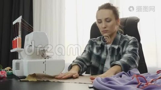 女人在裁缝工作室的桌子上用布料和剪刀`工作。 女人做手工服装。 缝纫面料车间。 F视频