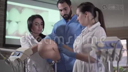 英俊的中东牙医向助手展示如何在口腔中使用设备。 高加索女性在练习视频
