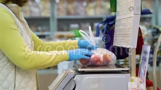 女顾客戴着医用手套，在杂货店里用秤称苹果视频