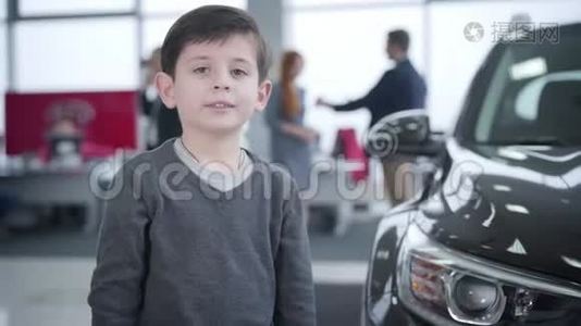 快乐的小白种人男孩在汽车经销店出现的画像。 在后台做交易的父母视频