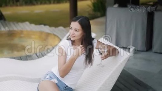 一个长头发的漂亮女孩端着杯子坐在沙发上视频