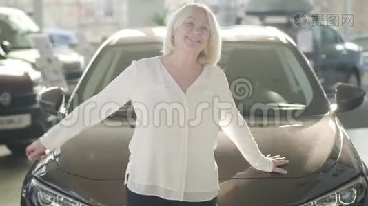 快乐成熟的白种人女人在新汽车旁边的经销商阳光下摆姿势的肖像。 快乐的高级夫人视频