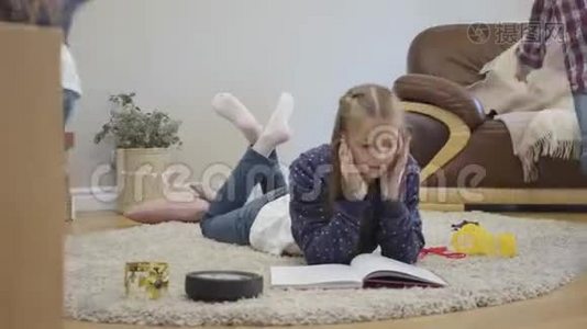 可爱的高加索女学生躺在柔软的地毯上，当她的弟弟妹妹四处奔跑时阅读的肖像。 小可爱视频