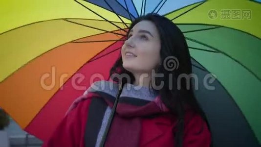 一幅美丽的白种人女孩的特写肖像，绿色的眼睛在背景上旋转着五颜六色的伞，微笑着视频
