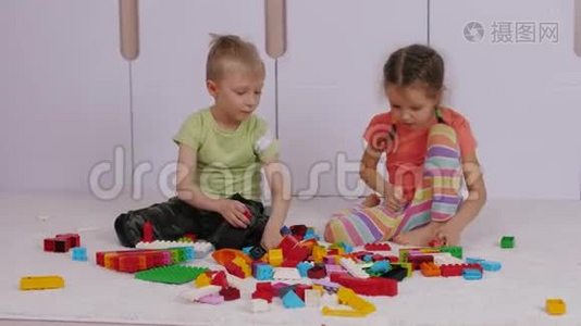 孩子们坐在地毯上玩五颜六色的乐高积木视频