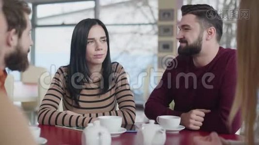 一对年轻的高加索夫妇在咖啡馆拥抱的肖像。 快乐的男人和女人和朋友坐在一起视频