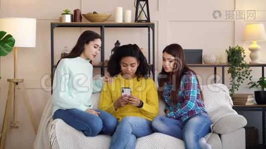 悲伤的多种族女孩在家中浏览智能手机上的社交媒体视频