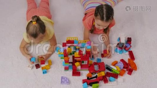 孩子们在游戏室里坐在地毯上玩彩色塑料构造器视频