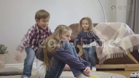 小白种人女孩和男孩跑到姐姐坐在地毯上拥抱她。 友好兄弟姐妹的肖像视频