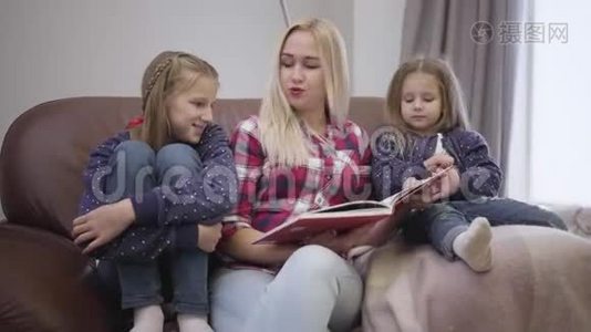 一幅美丽的高加索女人和女儿坐在沙发上看书的肖像。 母亲在家教育孩子视频