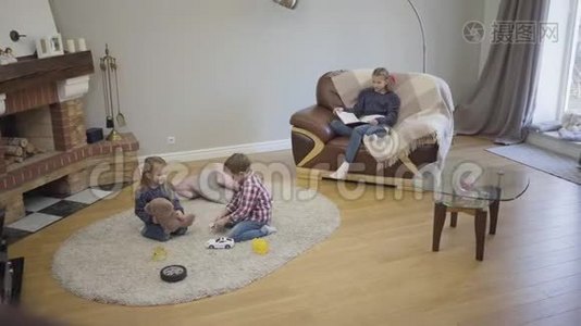 三个不同年龄的白种人儿童周末坐在家中壁炉前的长镜头。 年幼的孩子视频