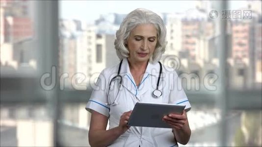 使用数字平板电脑的高级女医生肖像。视频