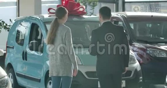 年轻的高加索男人和女人在经销商的新车前交谈。 从成功女商人的角度视频