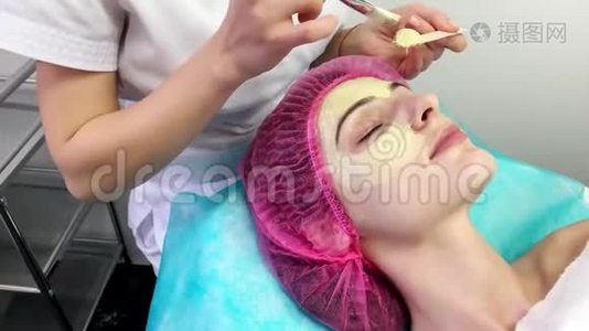 美丽的年轻女子在美容院接受面部护理。视频