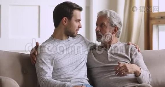 微笑的年轻人在家里和年迈的父亲交流。视频