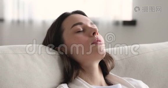 躺在舒适的沙发上睡着的轻松的年轻女子午睡视频
