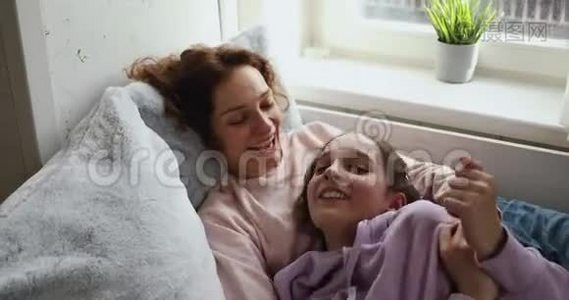 快乐的母亲和青春期的女儿在家玩着挠痒痒视频