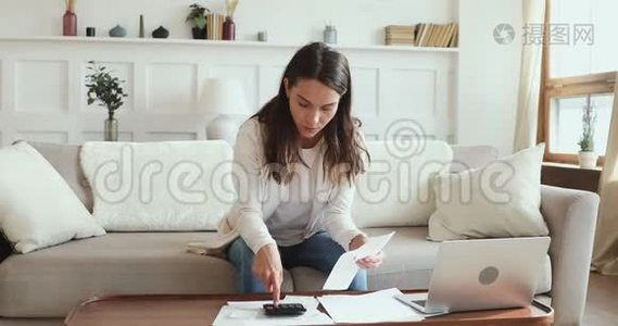 一个认真的年轻女人在家看文书工作计算账单视频