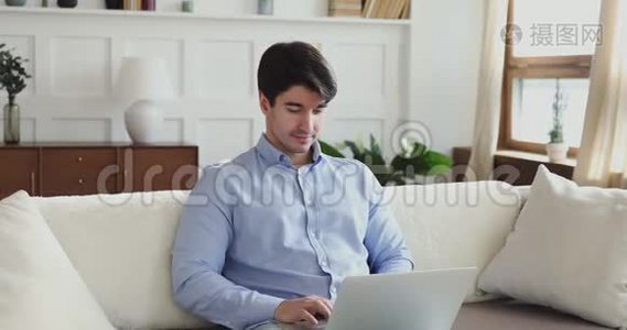 千禧一代用笔记本电脑坐在客厅的沙发上视频