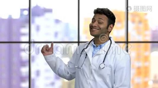 年轻的深色皮肤的印度教医生旋转着，用拇指指向后面。视频