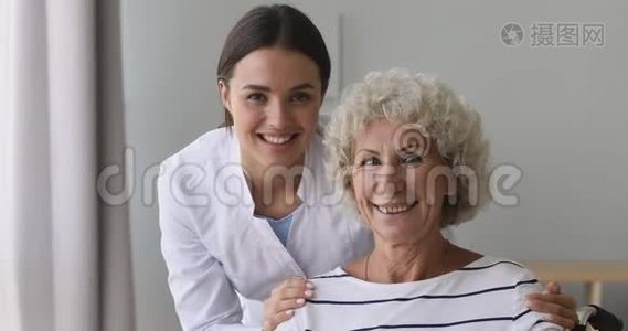 微笑着年轻的医务工作者拥抱着快乐的70年代养老金领取者的肩膀。视频