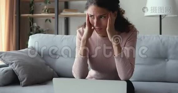担心的女人看着笔记本电脑，感到沮丧，读坏消息视频