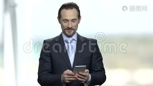 微笑的商人在他的智能手机上阅读信息。视频