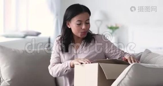 兴奋的非洲女顾客打开包裹箱坐在沙发上视频