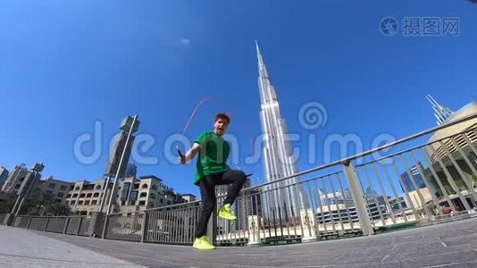 人用跳绳在迪拜的城市景观背景上跳跃。 慢动作视频
