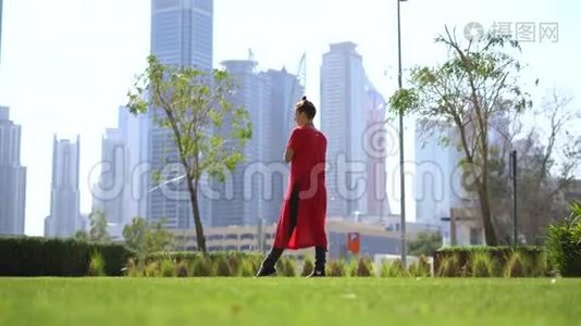 年轻女孩用跳绳在草地上跳跃，以迪拜的城市景观为背景视频