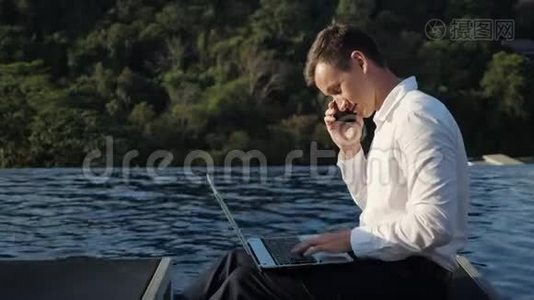 男人用笔记本电脑对着森林和游泳池打电话视频
