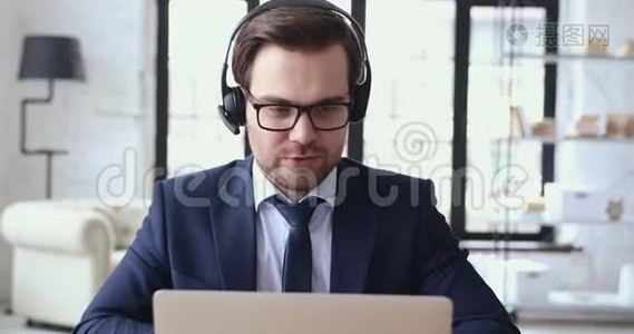 男性高管戴着耳机视频，通过笔记本电脑摄像头通话视频