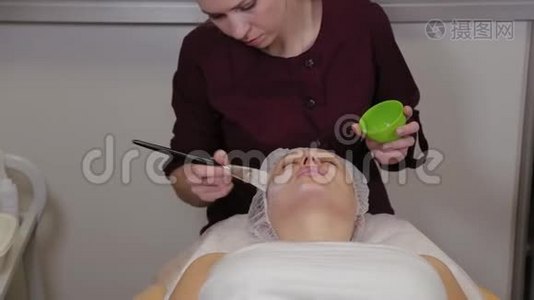专业美容师女性在病人脸上戴面具。视频