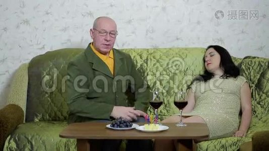 一对相爱的幸福夫妇坐在桌子旁的沙发上喝红酒视频
